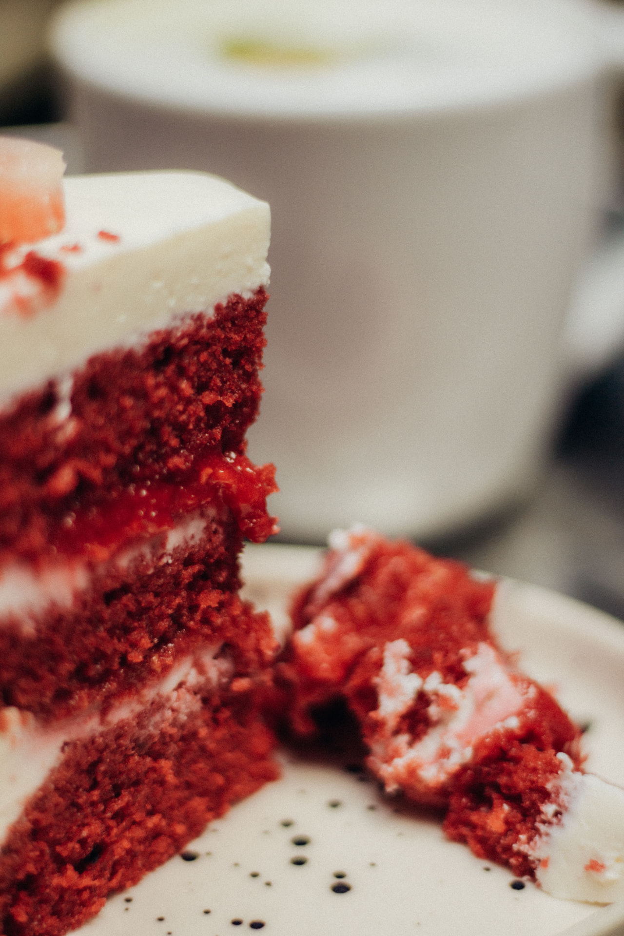 A sliced three-layer red velvet cake with deep red crumb and thick white frosting on a holiday table